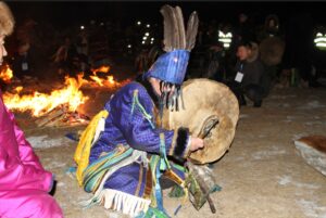 Mongolian Shaman in regalia beating drum